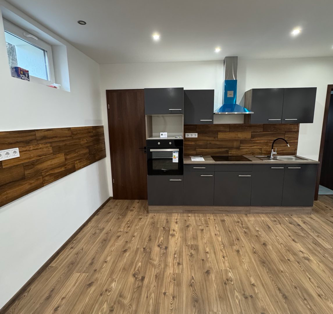 Modern style kitchen with black furniture and brown wood-inlaid wall cladding.