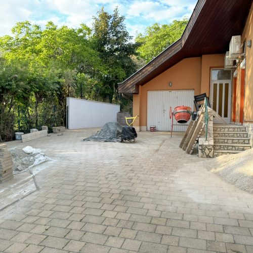 Property maintenance in action: the process of paving and fence construction on a driveway under construction.