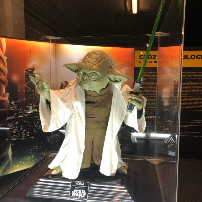 Star Wars exhibition installation: Master Yoda in a battle pose with a green lightsaber in his hand.